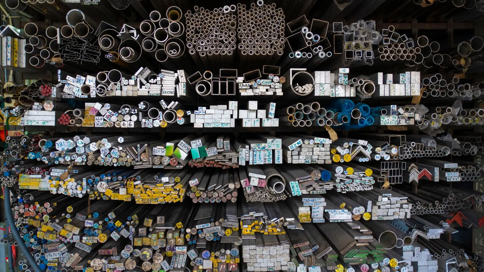Barres et profilés en acier, inox et aluminium rangés côte à côte dans un stock