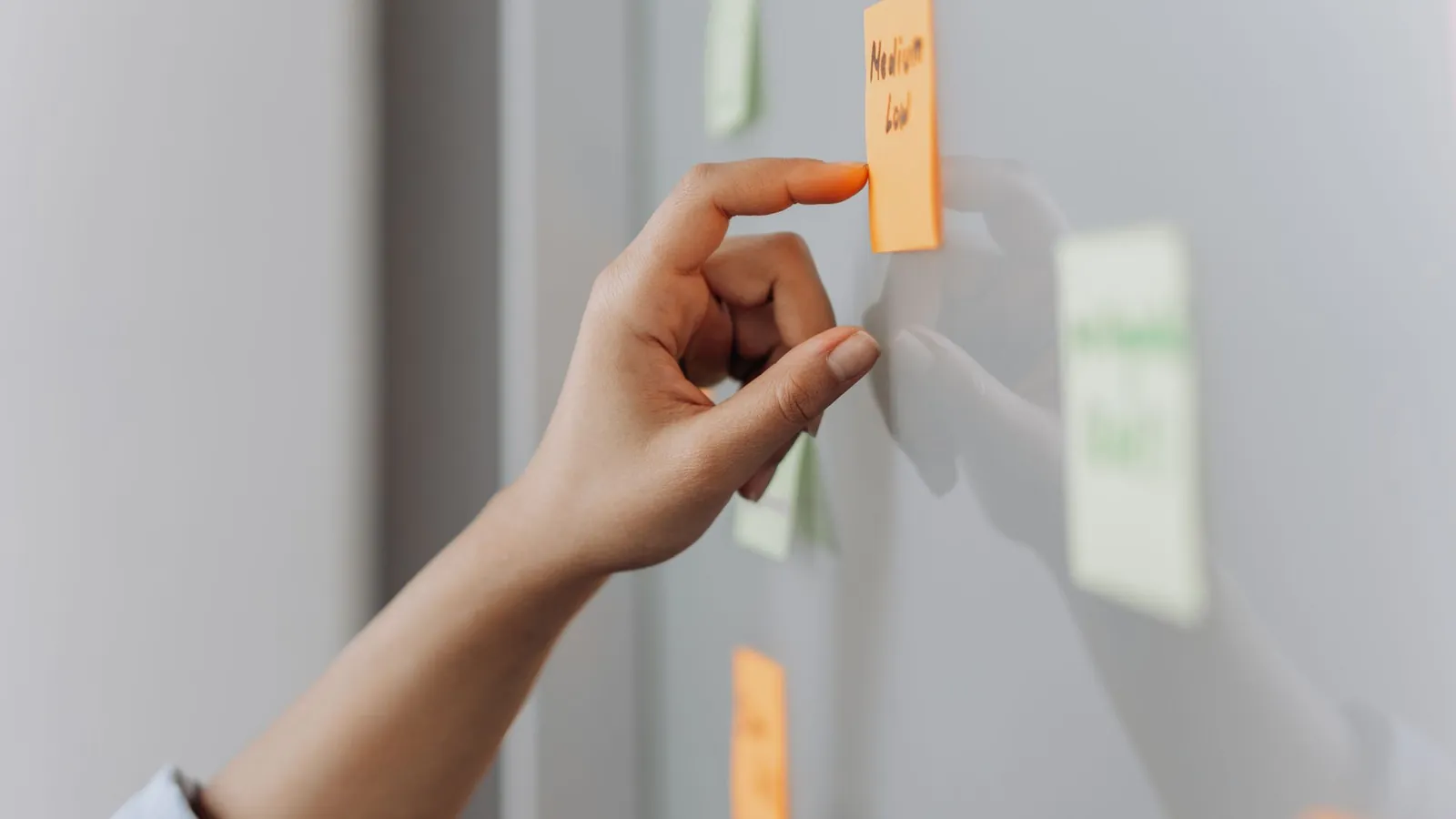 Main posant une note adhésive sur un mur de travail pendant une séance d'analyse