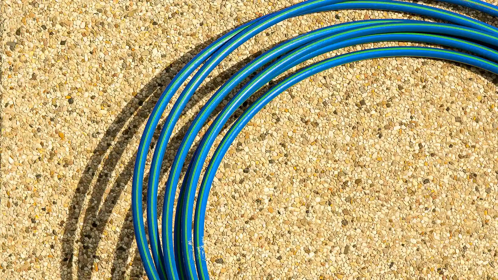 Tuyau souple bleu en matière synthétique enroulé sur un sol en gravillons