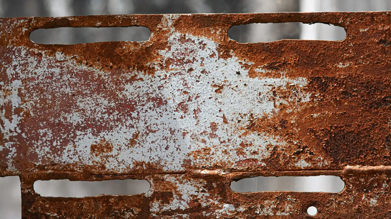 Tôle d'acier perforée couverte de rouille et de restes de peinture écaillée