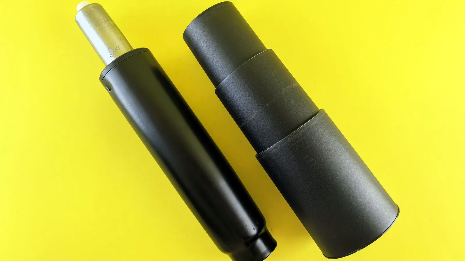 Deux corps cylindriques en acier à revêtement noir mat posés sur un fond jaune