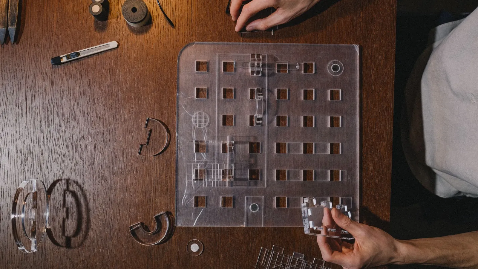 Plaque de plastique transparent découpée et pièces transparentes posées sur une table en bois