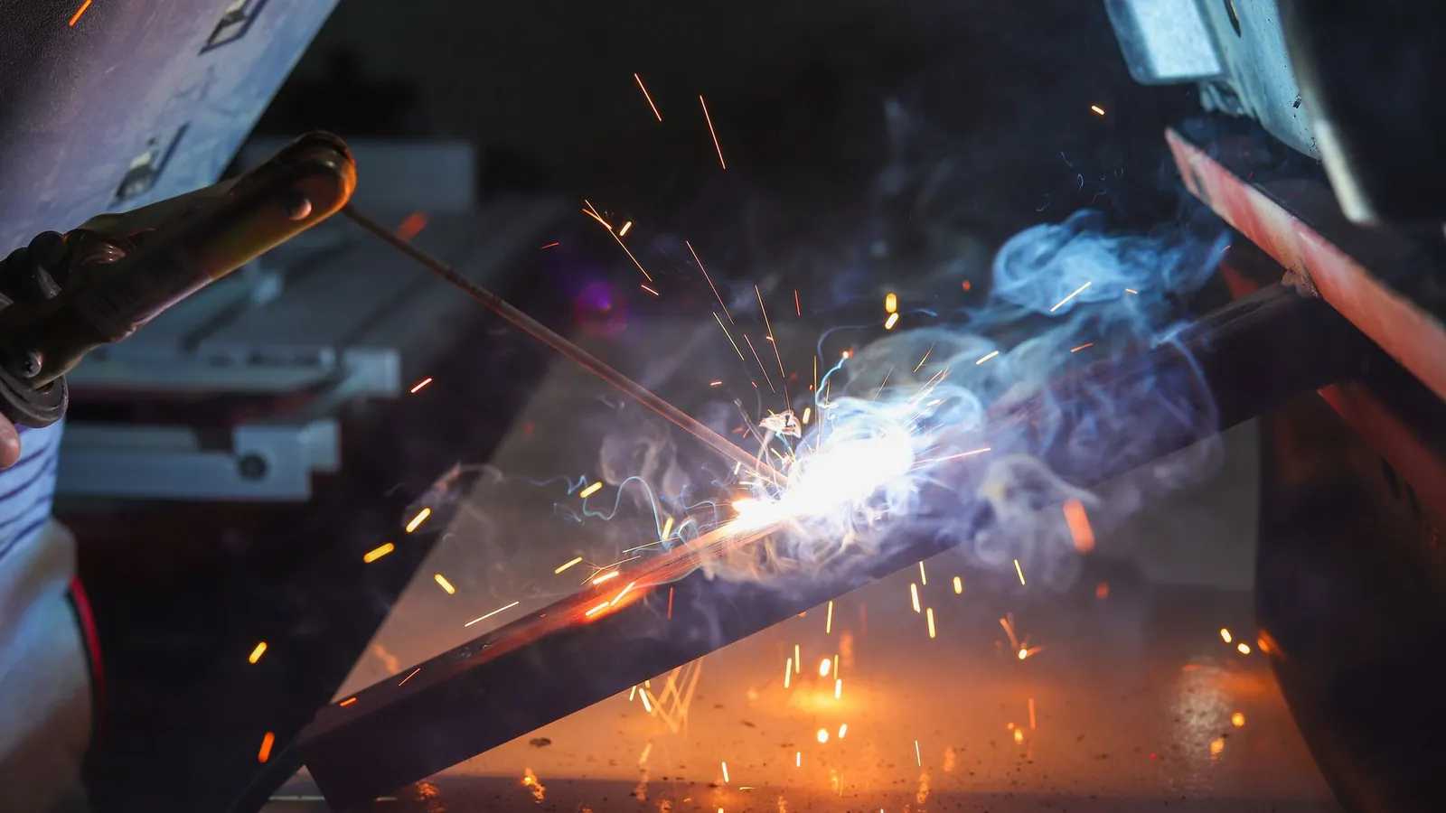 Soudage à l'électrode enrobée sur un profilé en acier, étincelles et fumée autour de l'arc