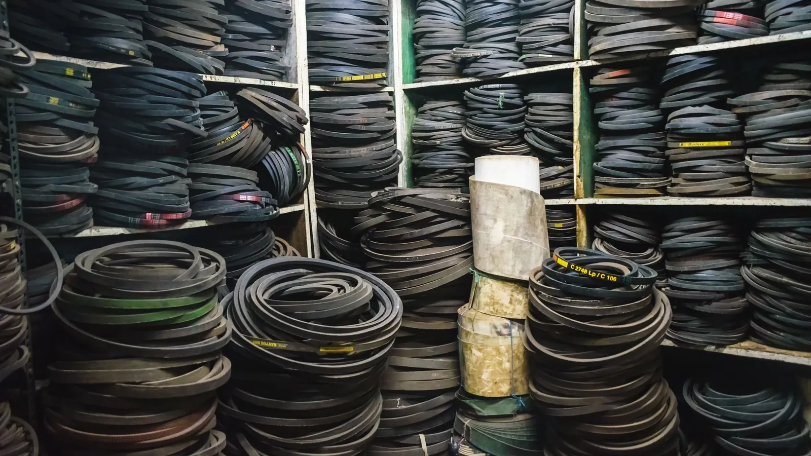 Courroies trapézoïdales en caoutchouc empilées par tailles sur les étagères d'un magasin de pièces