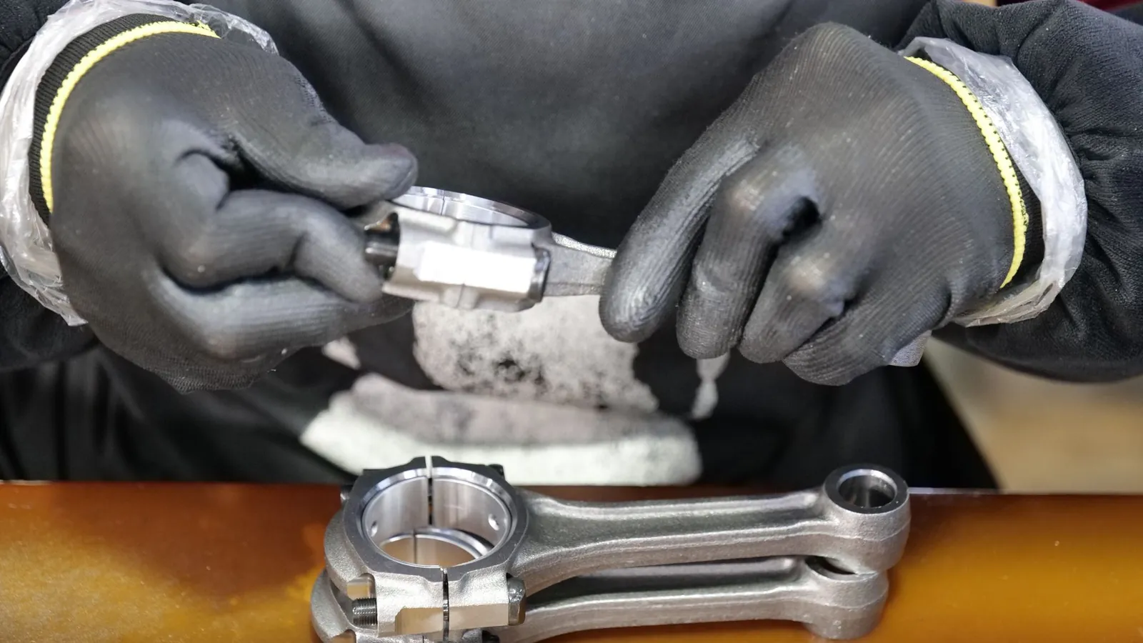 Assemblage d'une bielle aux mains gantées sur un poste de montage
