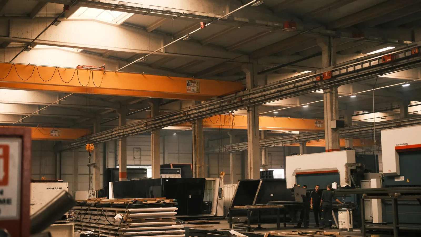 Halle de tôlerie-chaudronnerie équipée d'un pont roulant orange, de presses plieuses et de piles de tôles
