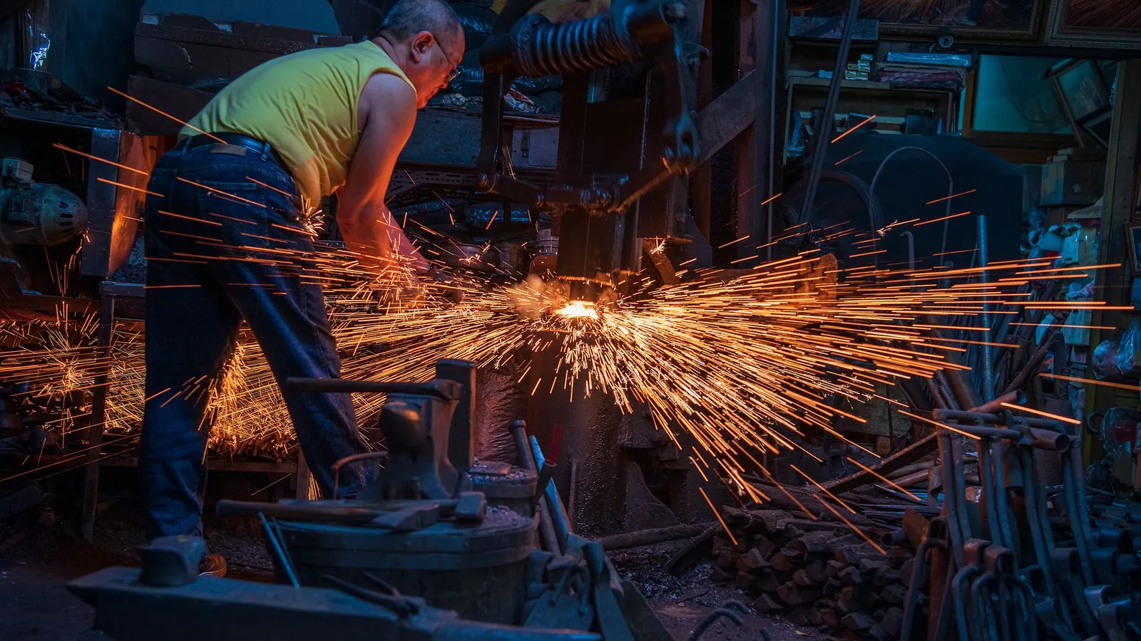 Forgeron travaillant une pièce chaude dans un atelier encombré, entouré d'une gerbe d'étincelles