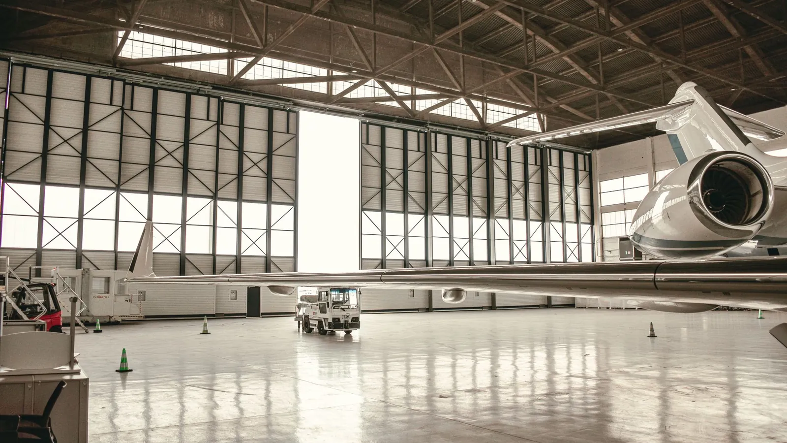 Avion d'affaires stationné dans un hangar de maintenance aux grandes portes vitrées