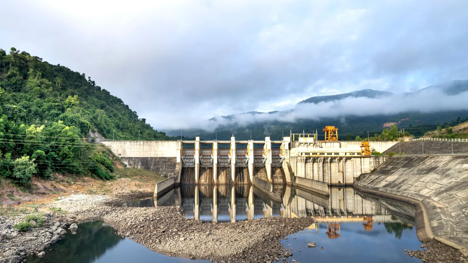 Barrage hydroélectrique et ses passes de déversement au fond d'une vallée boisée