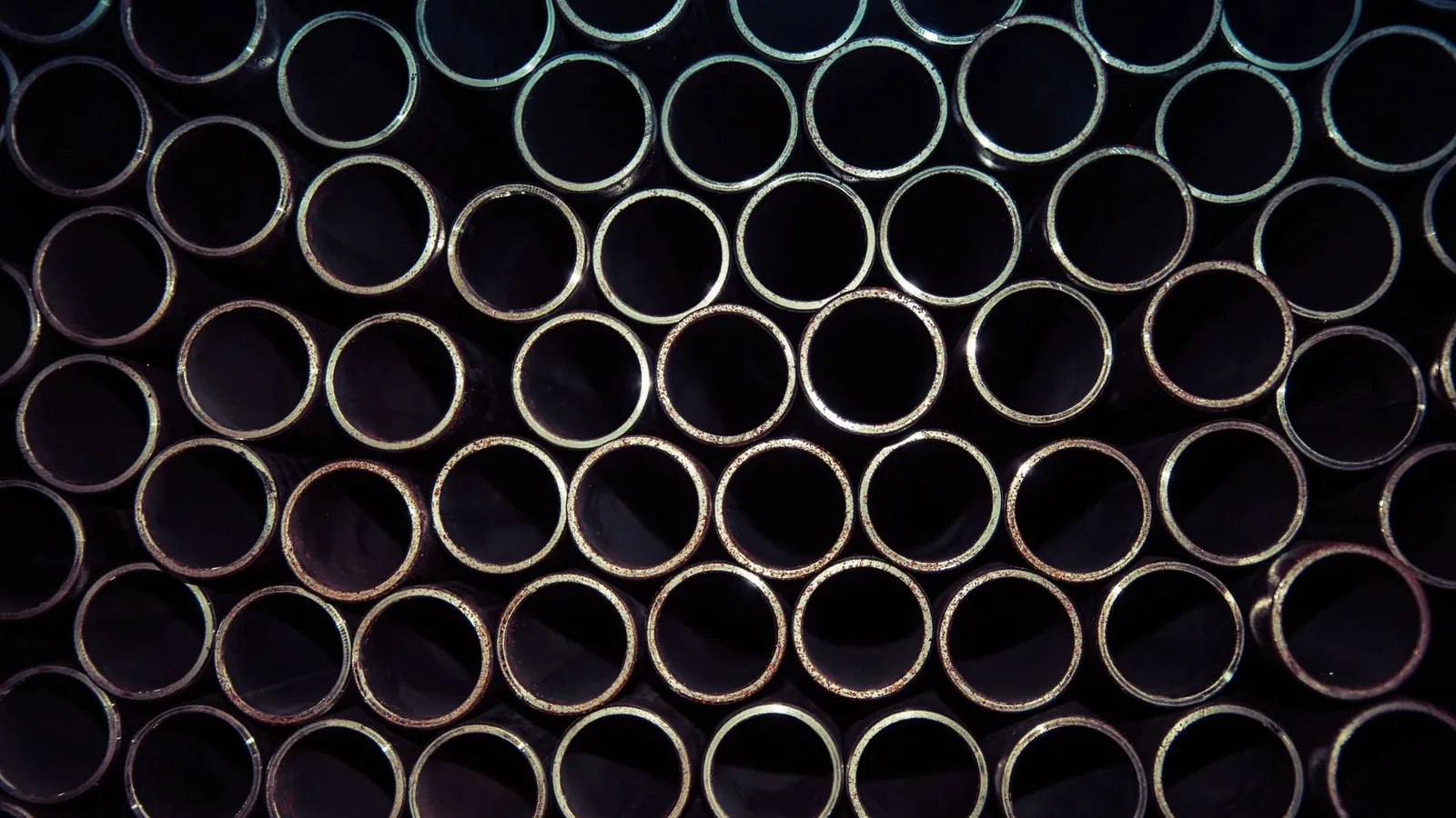 Tubes métalliques étirés empilés, vus en bout, formant un motif régulier de cercles