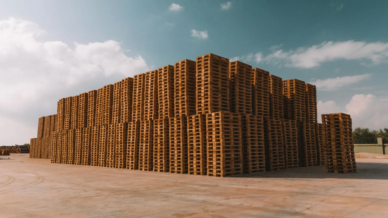 Grandes piles de palettes en bois stockées en plein air sur une aire de chargement