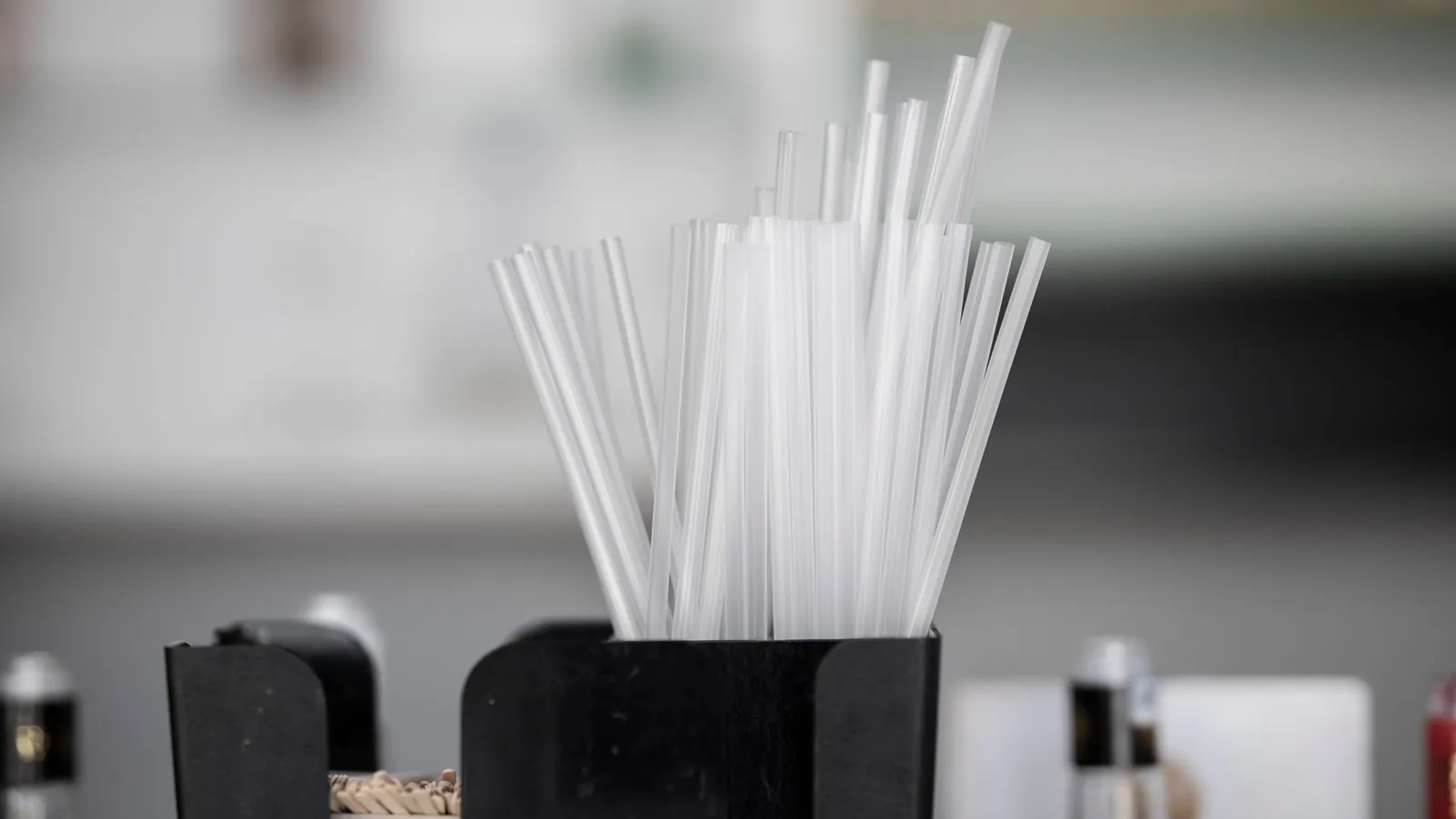 Pailles en plastique transparent extrudé, rangées debout dans un pot noir