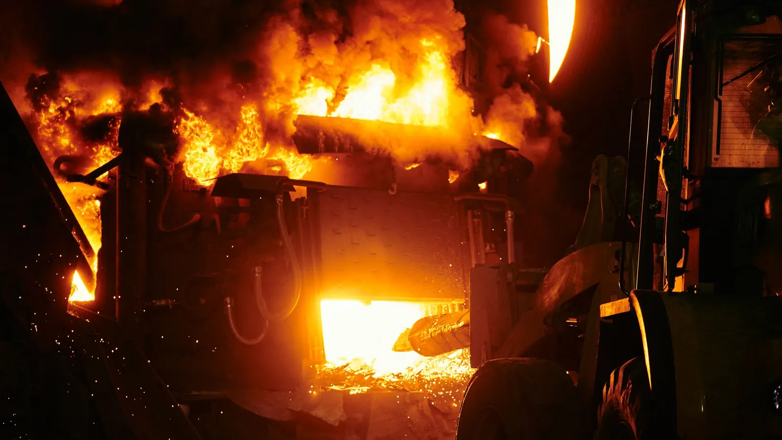 Four industriel en pleine chauffe, flammes et métal incandescent visibles par l'ouverture