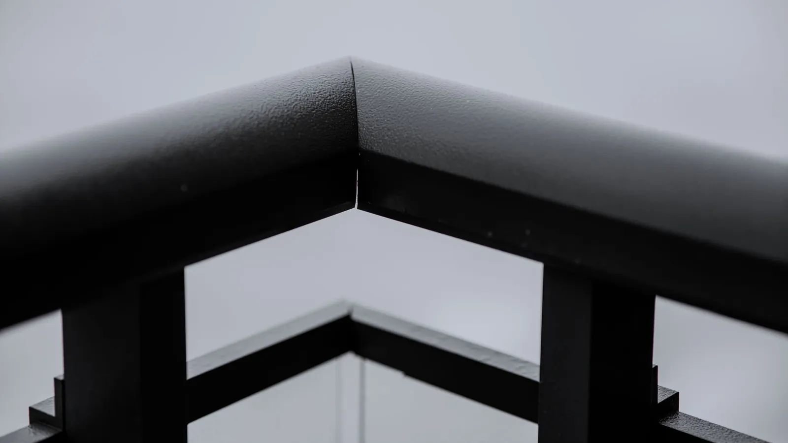 Main courante et garde-corps en acier laqué noir mat, vus à l'angle d'une terrasse