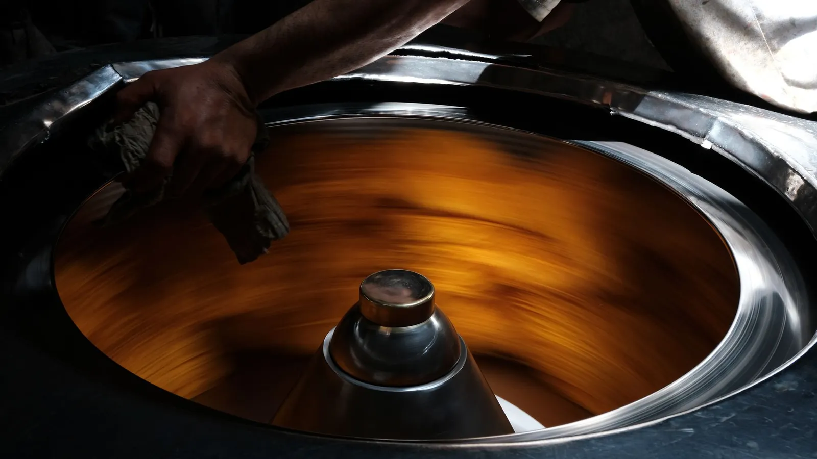 Repoussage au tour : un flan de tôle épousant un mandrin en rotation, maintenu par l'outil du repousseur