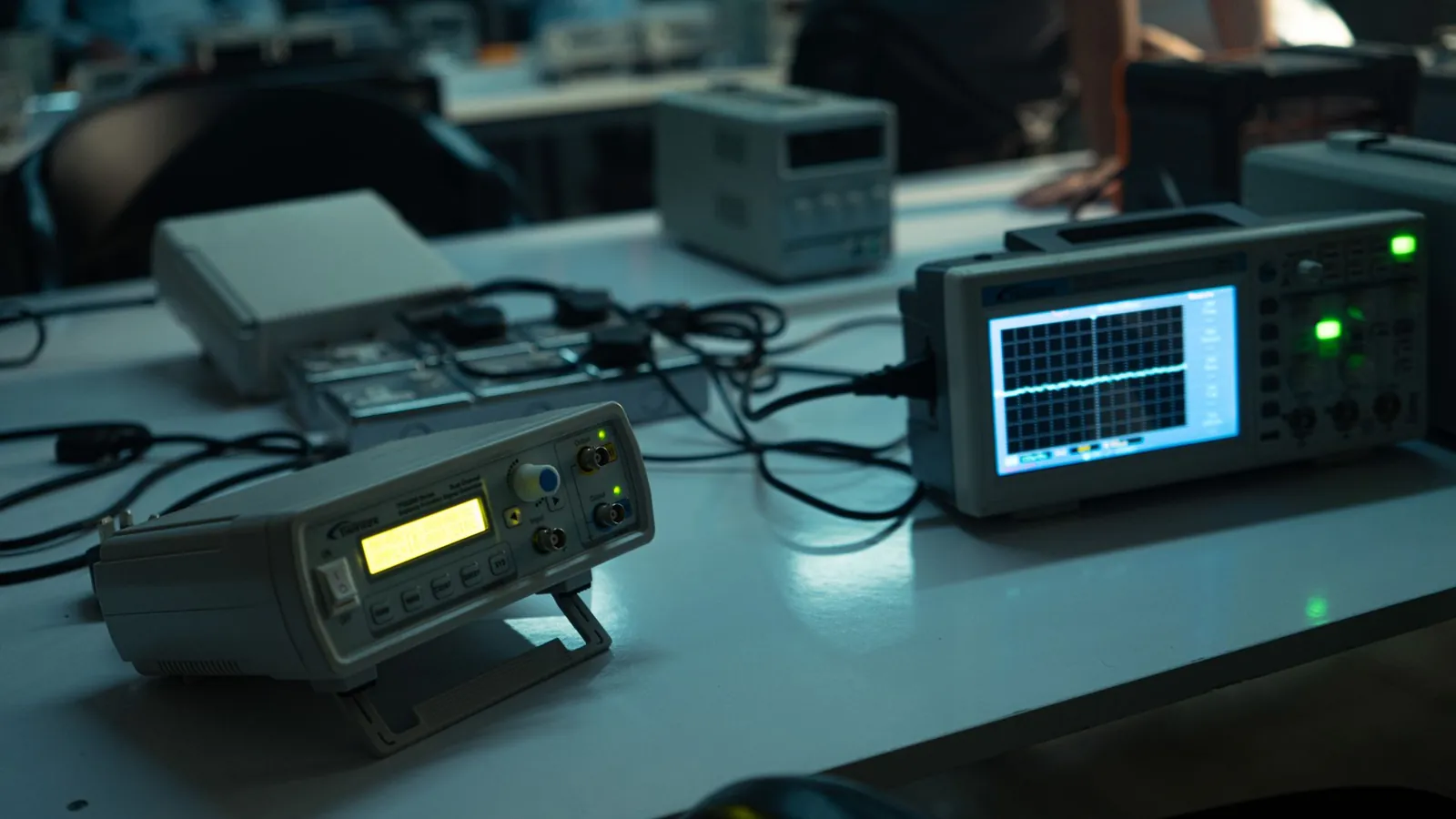 Banc de test électronique : générateur de fonctions et oscilloscope affichant un signal sur une paillasse de laboratoire