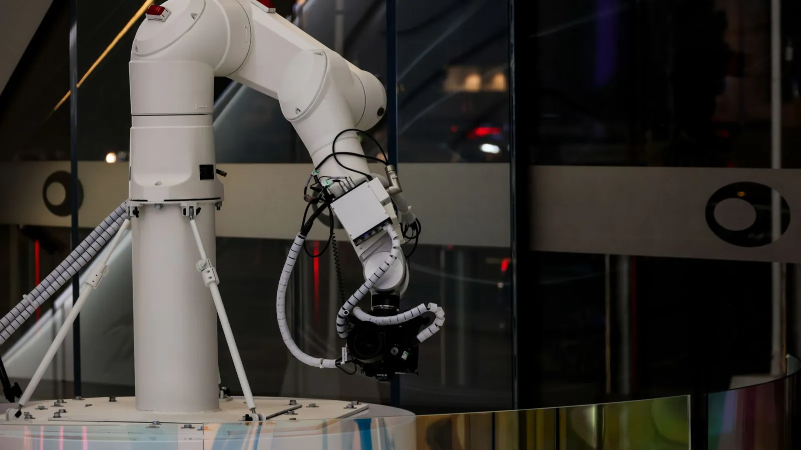 Bras robotisé articulé blanc à six axes, son faisceau de câbles guidé le long des segments