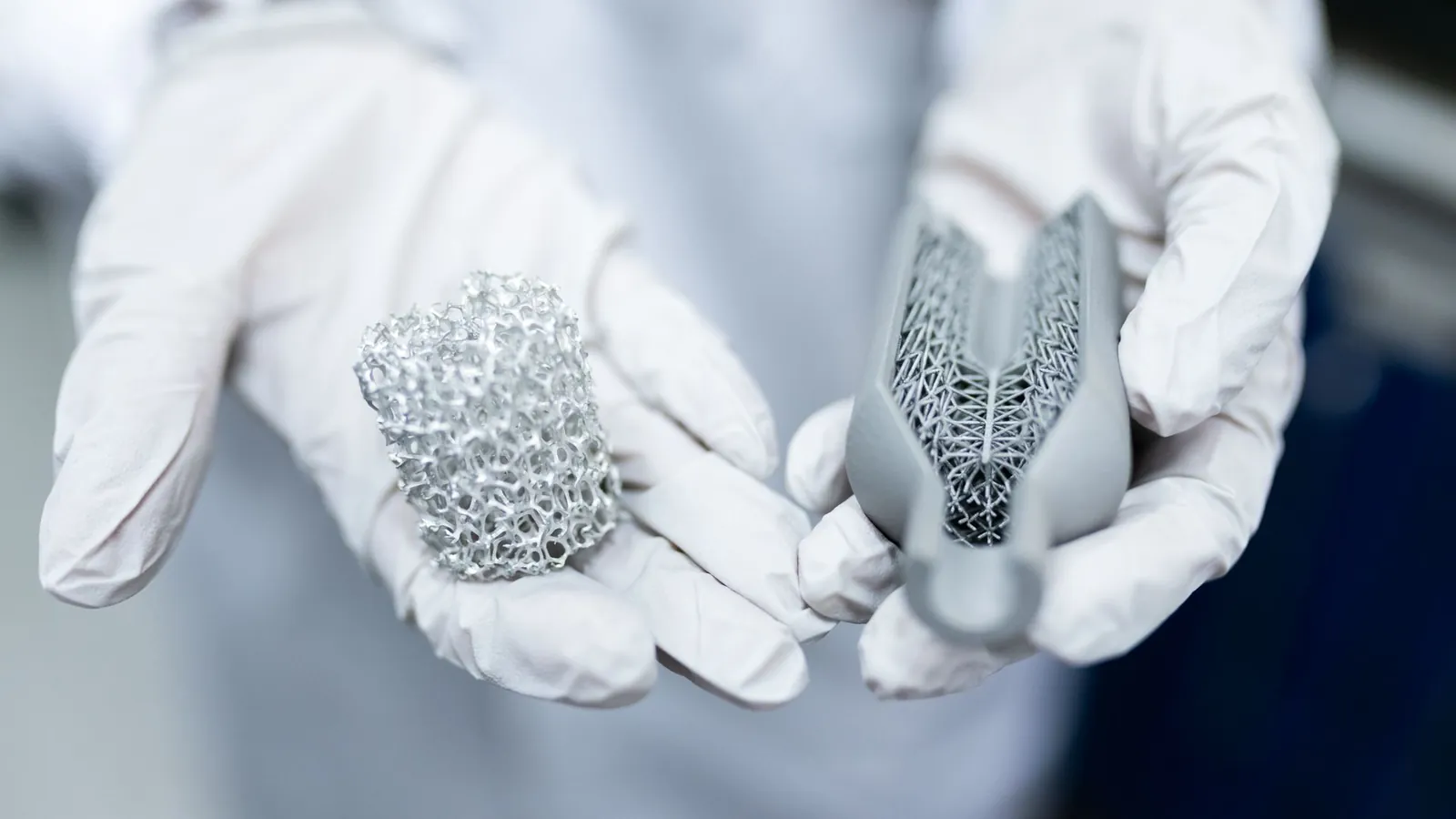 Pièces métalliques en structure lattice issues de fabrication additive, présentées dans des mains gantées