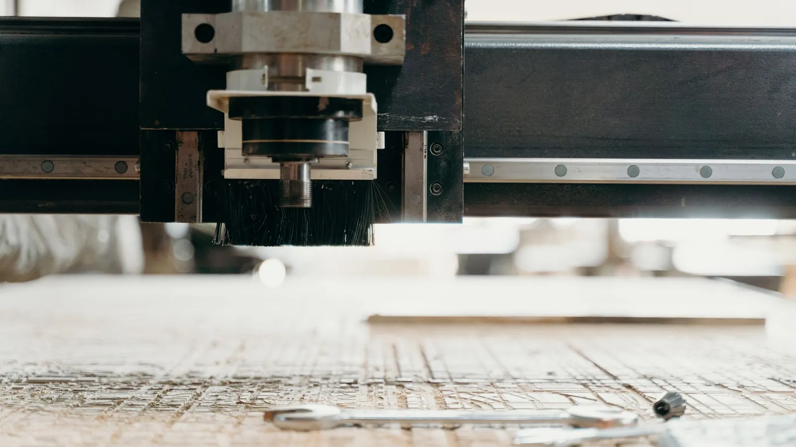 Défonceuse à commande numérique usinant un panneau de bois, sciure répandue sur la table