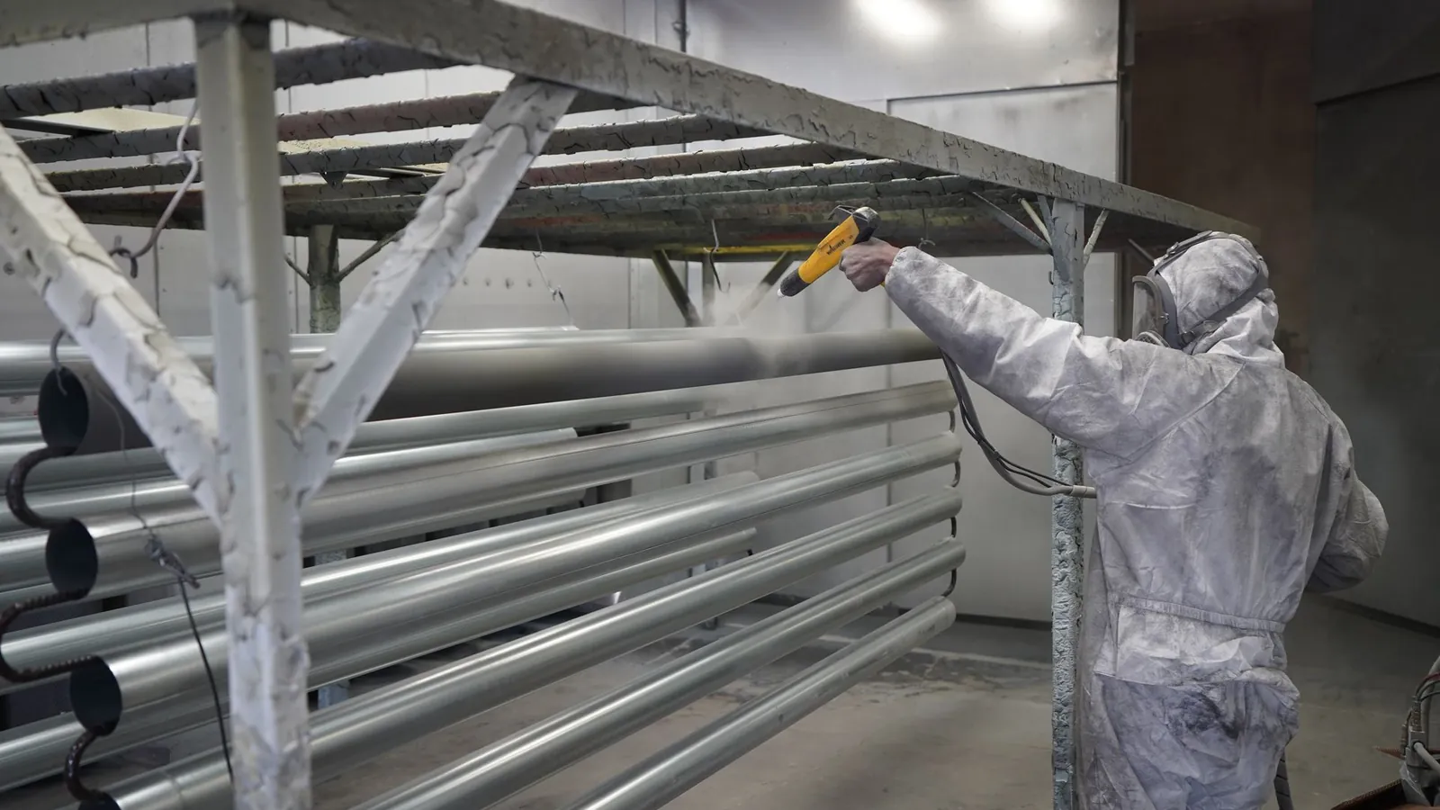 Application de peinture poudre au pistolet électrostatique sur des tubes suspendus en cabine