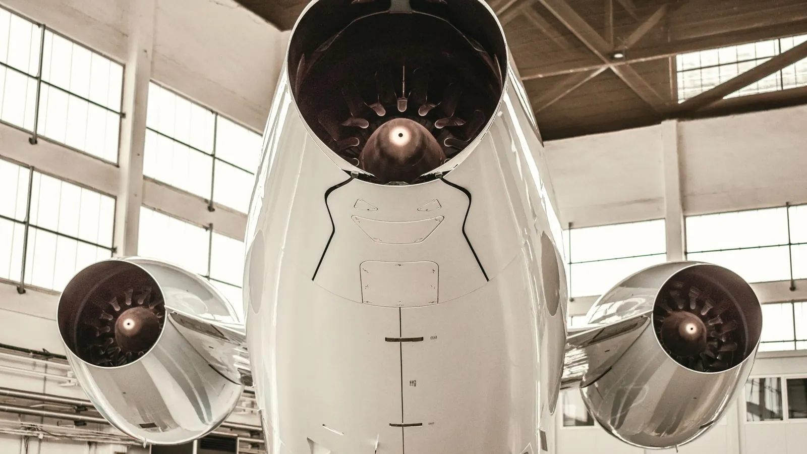 Deux réacteurs d'un avion vus par-dessous dans un hangar de maintenance, nacelles et tuyères visibles