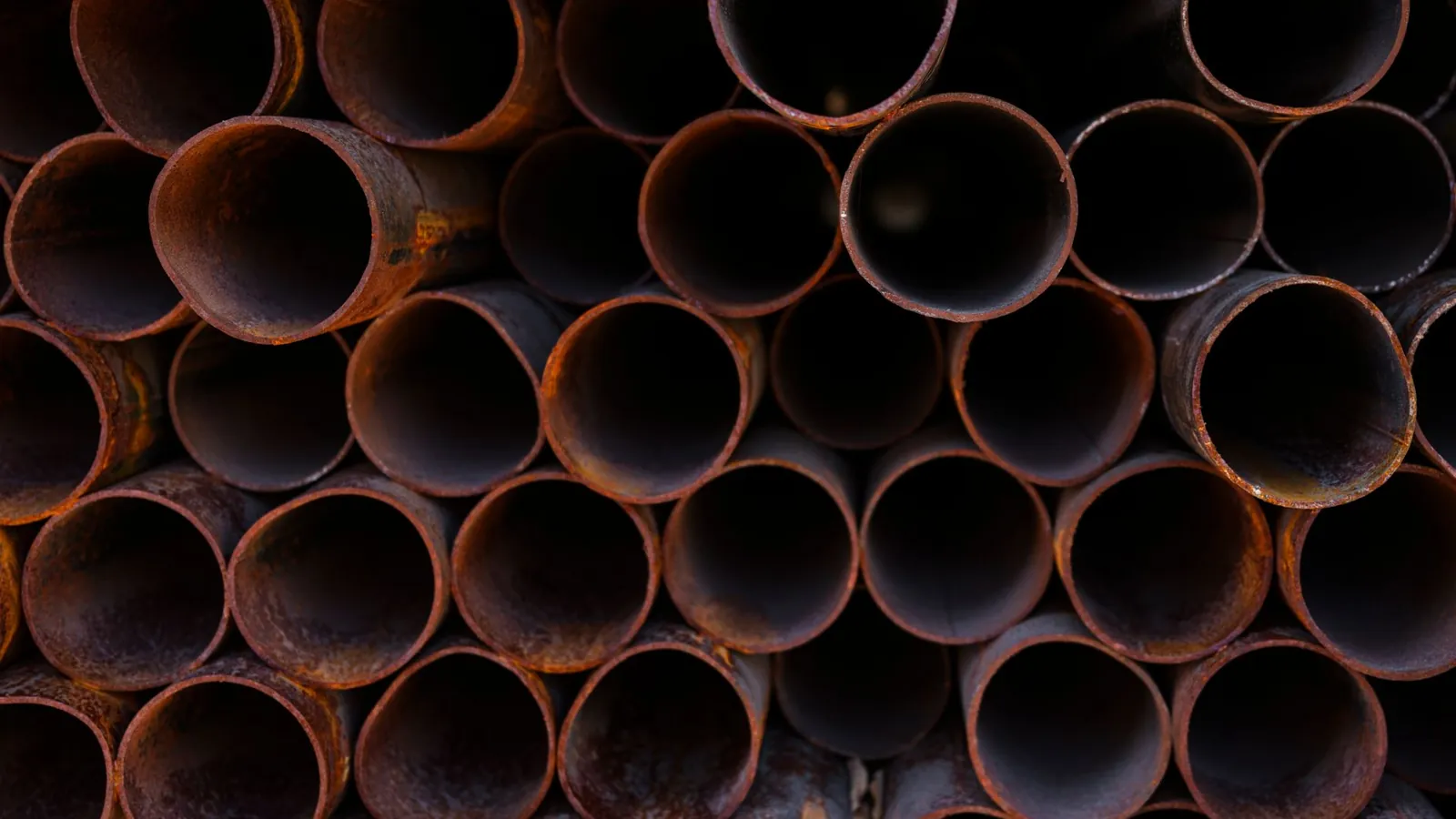 Tubes ronds en acier noir empilés en fagot, extrémités rouillées vues de face