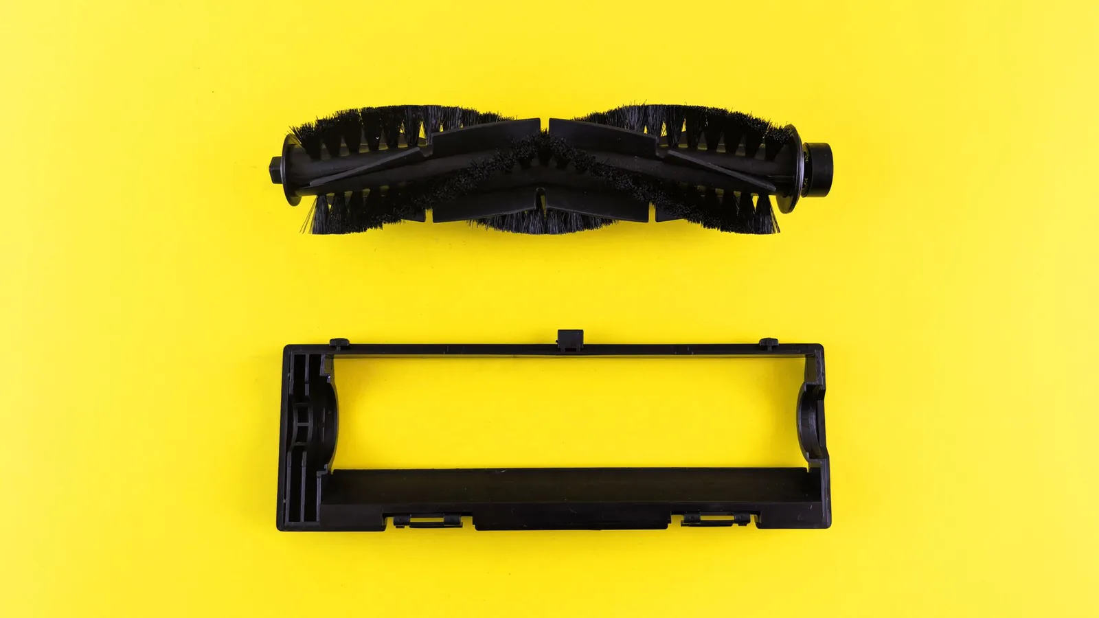 Cadre en plastique noir injecté et brosse rotative posés sur un fond jaune