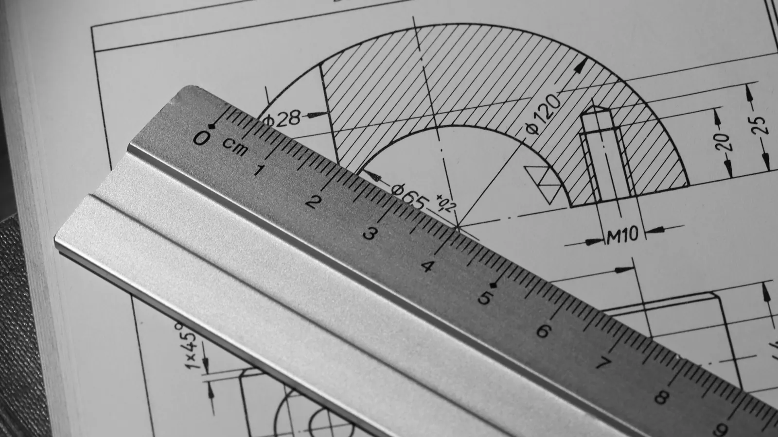 Règle graduée en aluminium posée en travers d'un dessin technique en coupe, diamètres et tolérance d'un alésage cotés