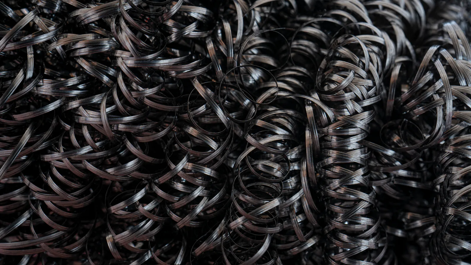 Amas de copeaux métalliques sombres enroulés en spirales serrées, vus en gros plan