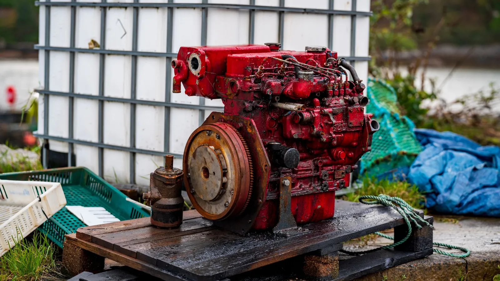 Moteur diesel industriel rouge posé et calé sur un plancher en bois, prêt à recevoir sa protection
