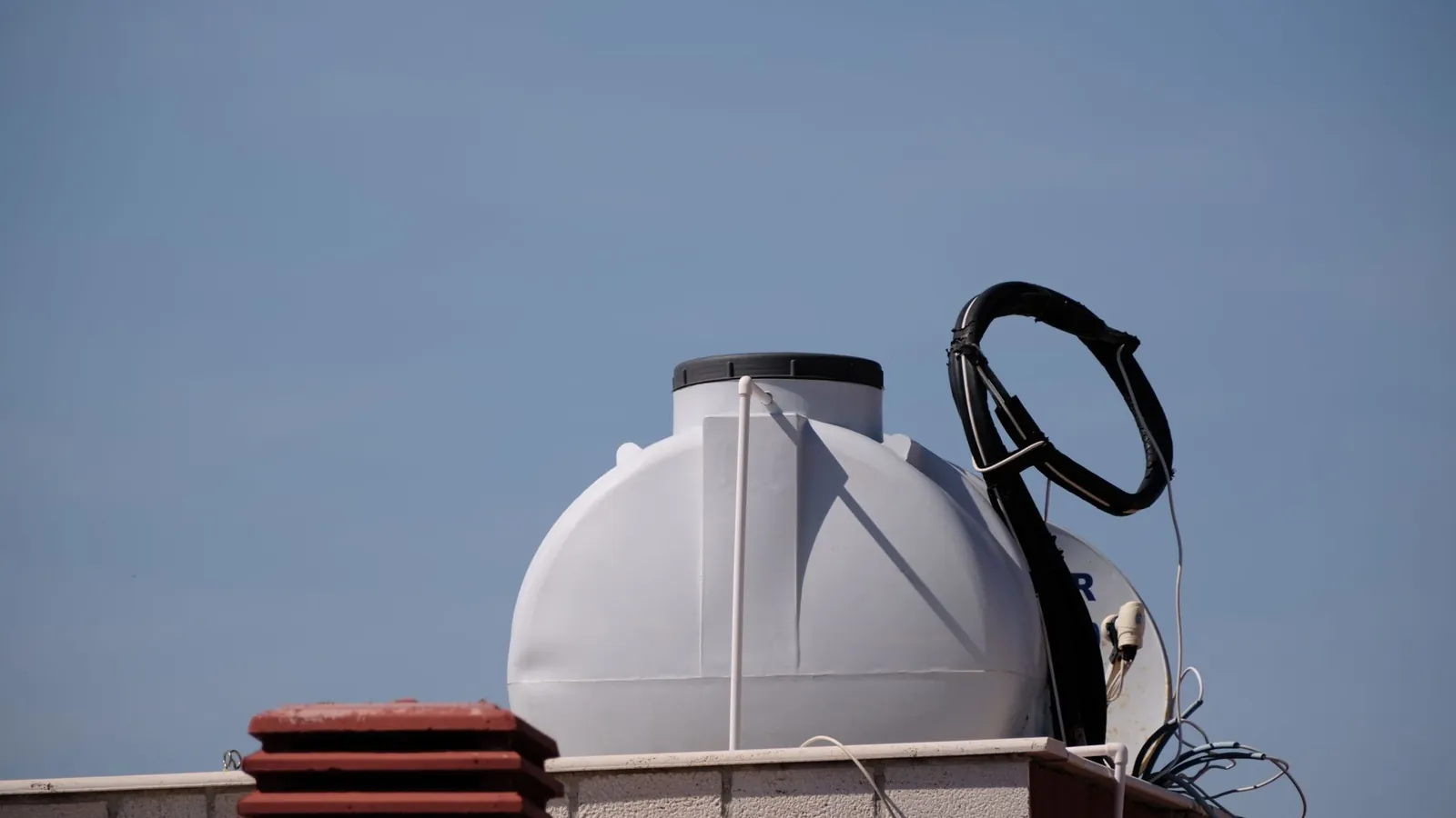 Cuve de stockage en polyéthylène blanc installée sur un toit-terrasse