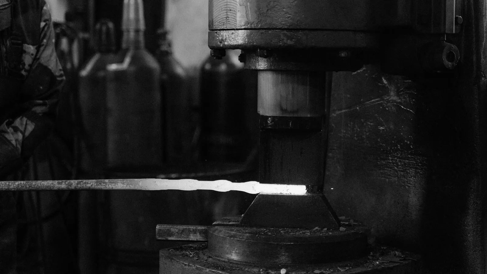 Barre incandescente posée sur l'enclume d'un marteau-pilon, en noir et blanc