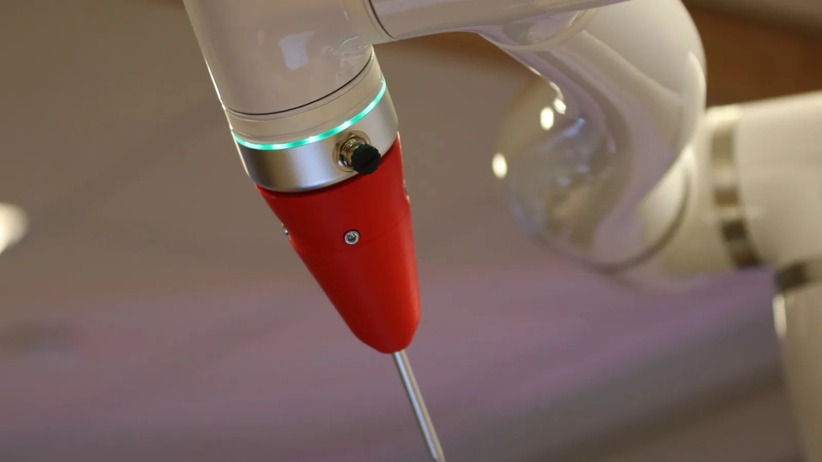 Poignet d'un bras robotisé collaboratif blanc équipé d'un outil rouge à pointe, en gros plan