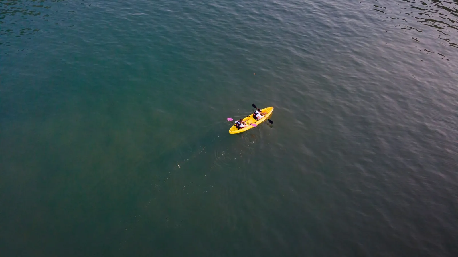 Kayak jaune monocoque vu d'en haut sur un plan d'eau sombre