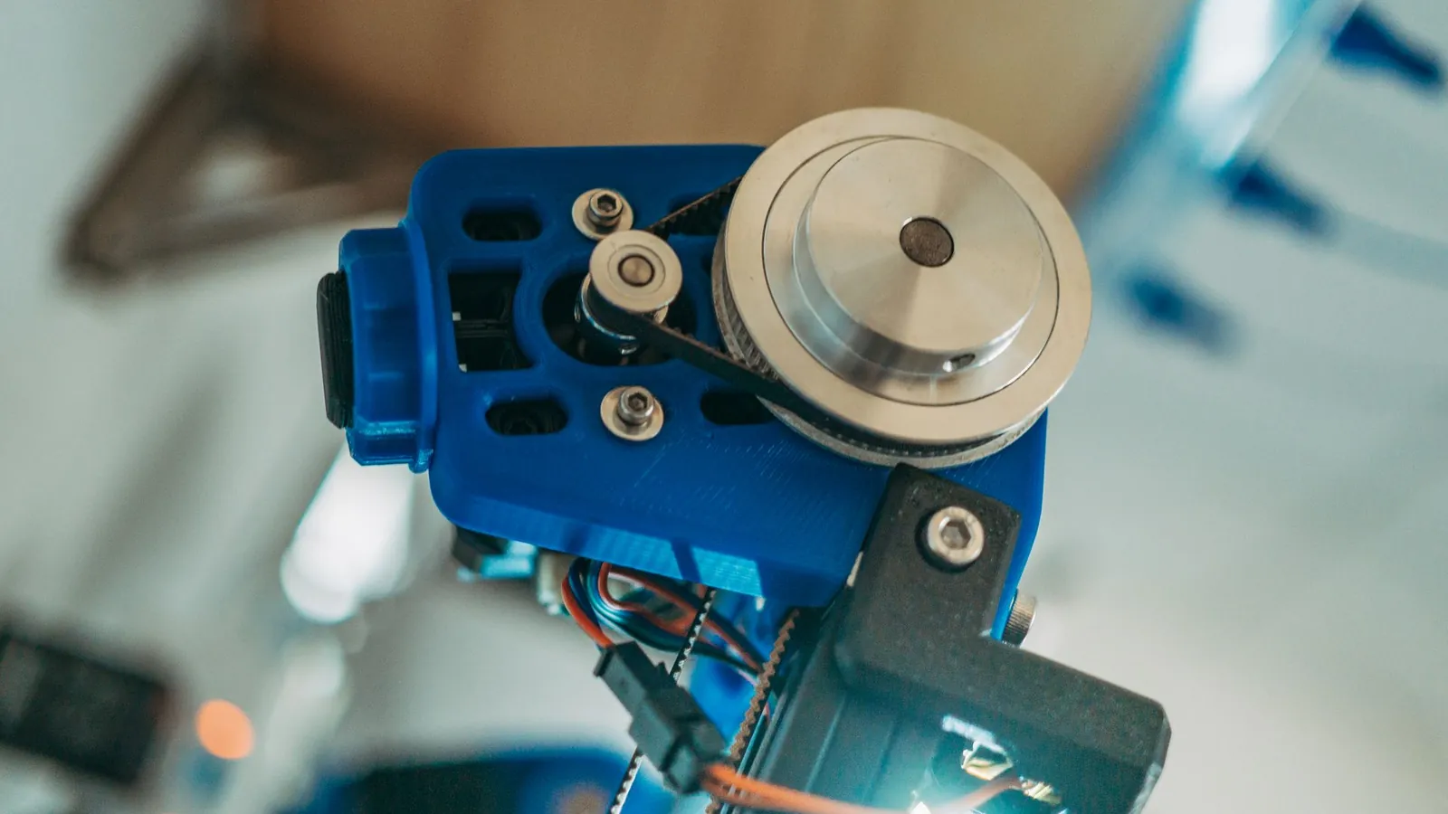 Poulie et courroie d'entraînement d'une imprimante 3D montées sur un support en plastique imprimé bleu